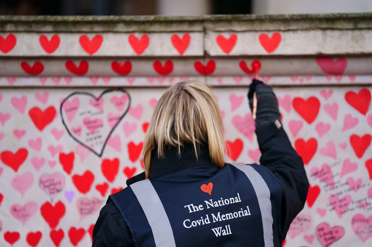 A volunteer from the Covid-19 Bereaved Families for Justice campaign group paints a heart on the National Covid Memorial Wall opposite the Palace of Westminster in central London, which remembers people who have died of the virus. Picture date: Friday January 28, 2022.