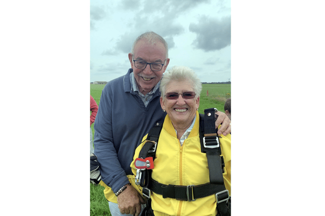 Angela Larkworthy having touched down on solid ground after her skydive is embraced by husband Gary