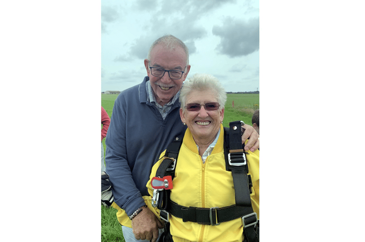 Angela Larkworthy having touched down on solid ground after her skydive is embraced by husband Gary