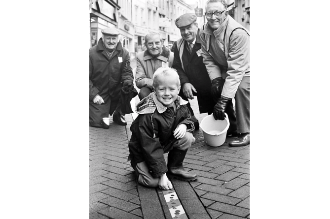 Five year old Christopher Beswick makes his contribution to the Moose Lodge line of pennies in Teignmouth’s Bank Street as part of the 1990  Children in Need appeal