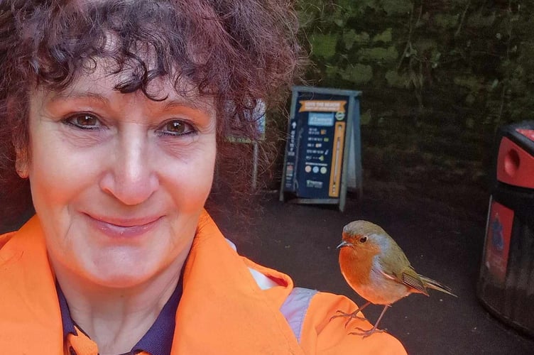 Dawn Kiff, 58 with a robin. Release date  March 19 2024. See SWNS story SWLNrobin. A woman who began feeding robins while on her coffee breaks says they now land on her head, sing to her  and even know her routine. Dawn Kiff, 58, began working as a cleansing operative in Shaldon, Devon, nine months ago, spending a lot of time in and around the heavily forested Smugglers Tunnel as a result. But over the past month, she has become a familiar face in the village  after befriending a family of friendly robins during her coffee breaks. I first noticed them back in October when the leaves were coming down and I had to clean around the tunnel, said Dawn. 