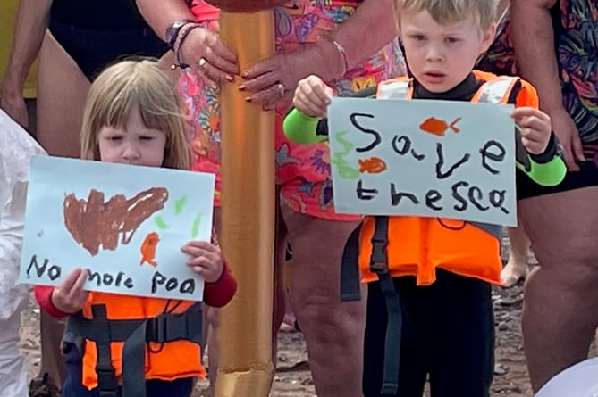 Children hold placards at the Teignmouth protest against sewage pollution.
