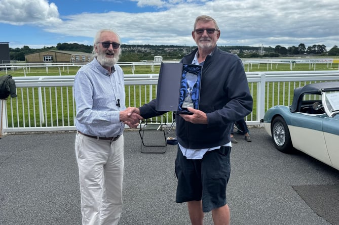 Frank Loft presents Will Edwards with the Best in Show award at the Newton Abbot Racecourse Antiques Fair and Classic Car Show