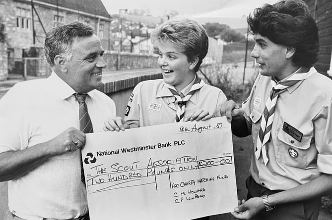 Kingskerswell Venture Sccouts were better off to the tune of £200 in August 1987. Venture Scout Kirsty Brooks and scout leader Ian Lee are pictured here receiving a cheque from George Dyson of the ARC Charity Matching Fund