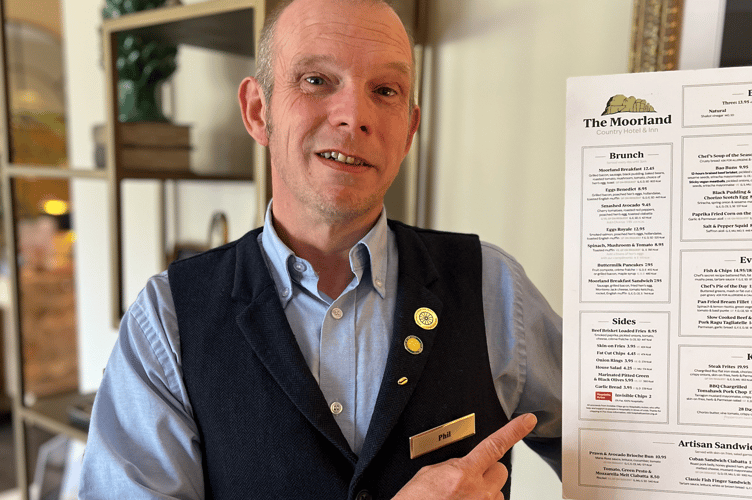 Trainee Deputy Manager Phil Masters with a copy of the menu, pointing to the Invisible Chips!