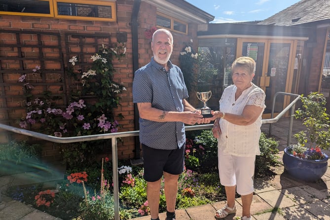 Victor Gillingwater receives his cup from judge Anne Hext for the communal garden category of the 2024 Teign Housing in Bloom competition.