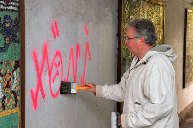 Councillor David Cox scrubs out graffiti in a Teignmouth underpass