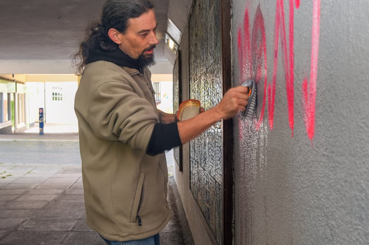 Councillor Dan Comer covers up graffiti in a Teignmouth subway