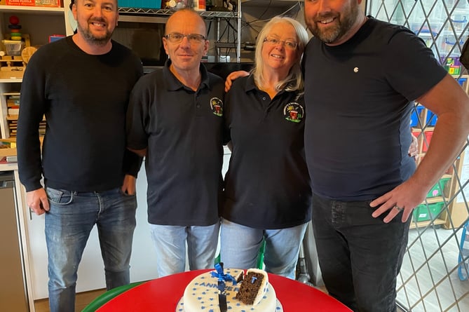 Local businessmen Jamie Ayre (L) and Byron Beacham (R) help Nicky and Paul Burgess (centre) to cut a cake to celebrate 25 years of childminding