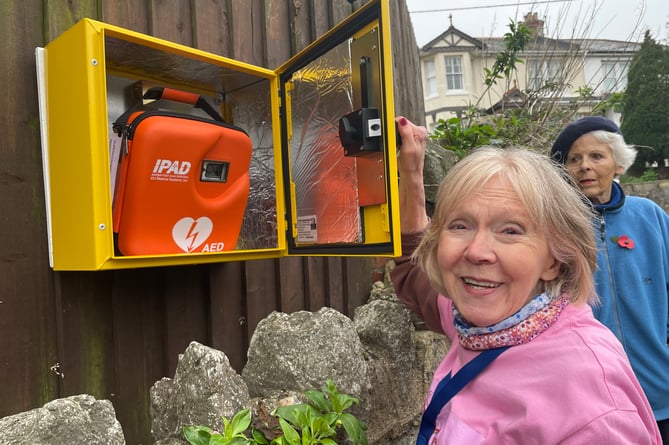 Teign Heartbeat founder and chair Shirley Brokenshaw puts the defibrillator into the new cabinet in a residential area of east Teignmouth